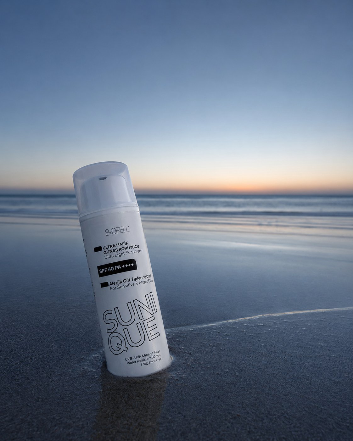 Sunique Allergy-Prone SPF 40 sunscreen bottle on wet sand at blue hour