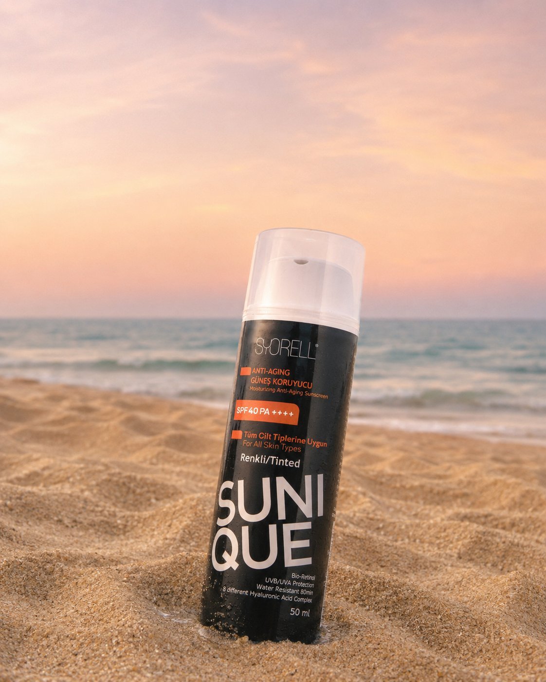 Sunique Anti-Aging Tinted SPF 40 sunscreen bottle on soft sand at dusk