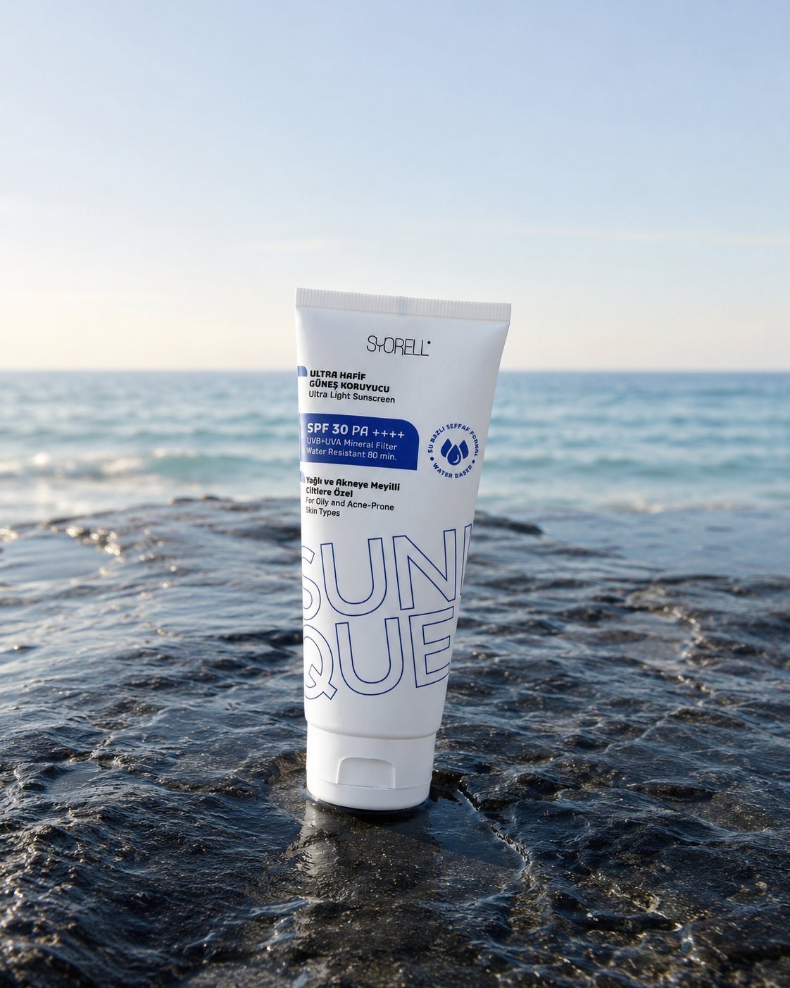 Sunique Oil Control Ultra Light SPF 30 sunscreen tube on wet dark coastal rock at soft sunrise