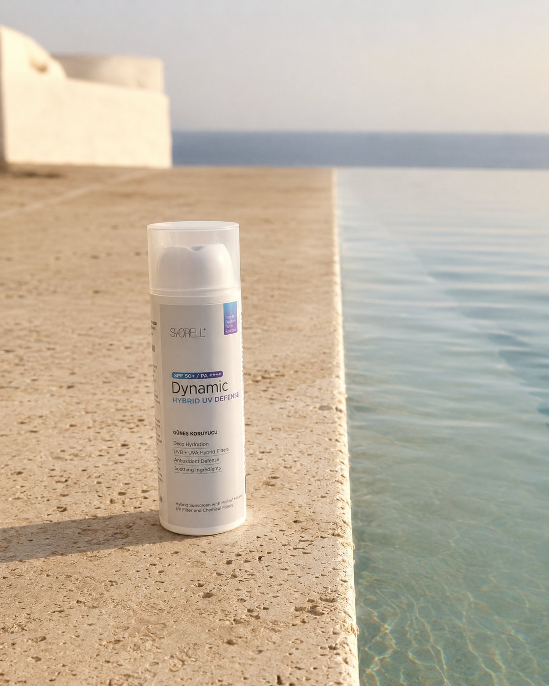 Dynamic Hybrid UV Defense SPF 50+ sunscreen on travertine pool edge with Mediterranean sea horizon